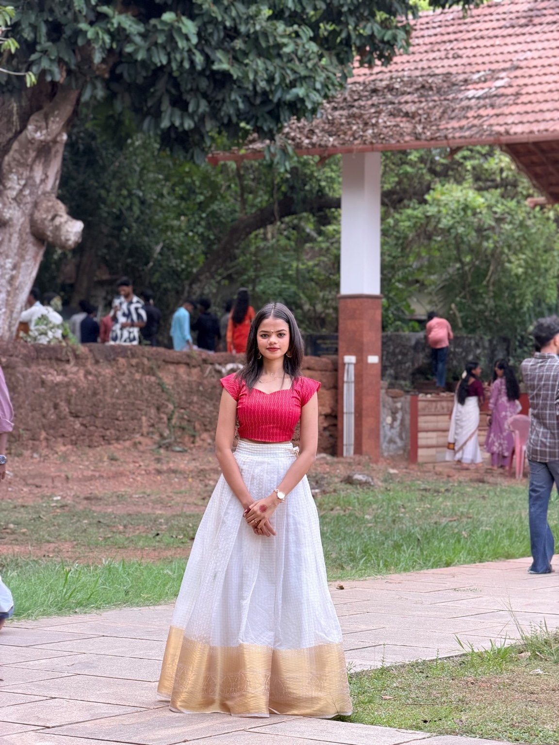 Punnya outdoors wearing a red blouse and white and gold skirt